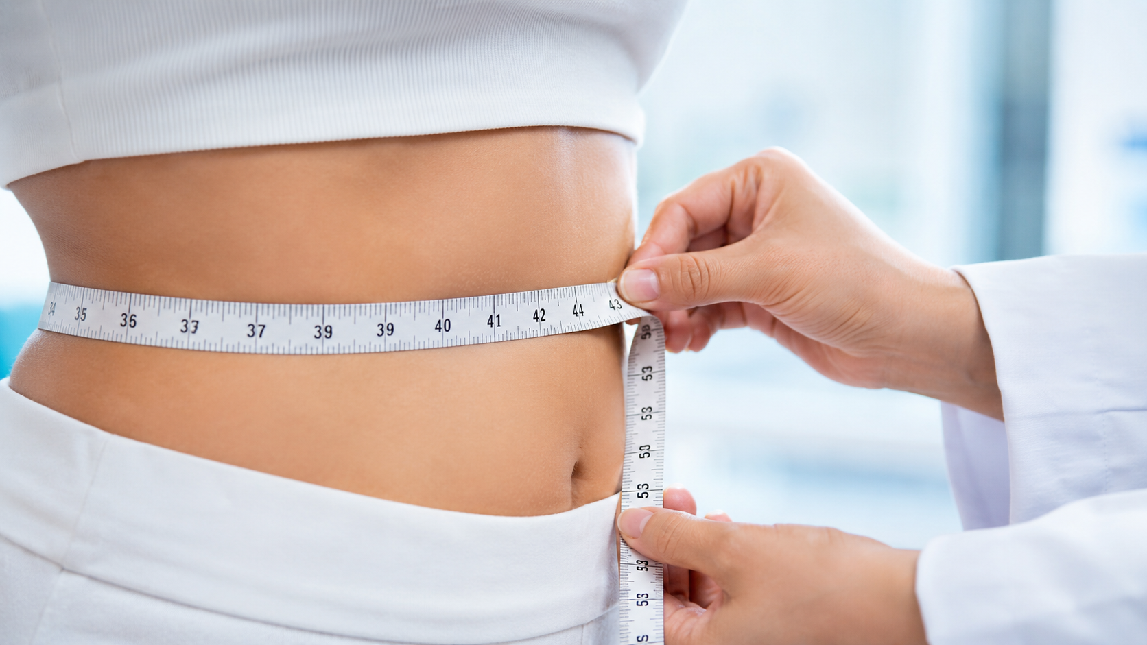 Clinician measuring waist circumference with a tape measure during body contouring assessment